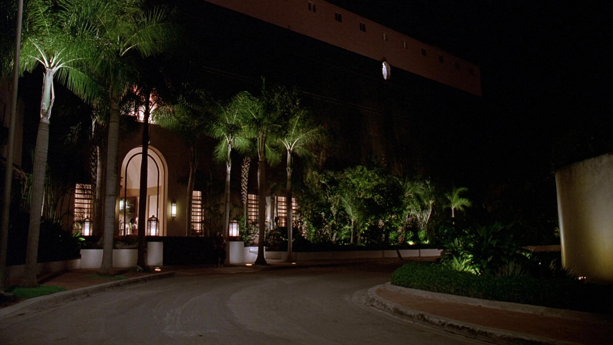 Boutique hotel exterior at night with palm trees and a lit entrance